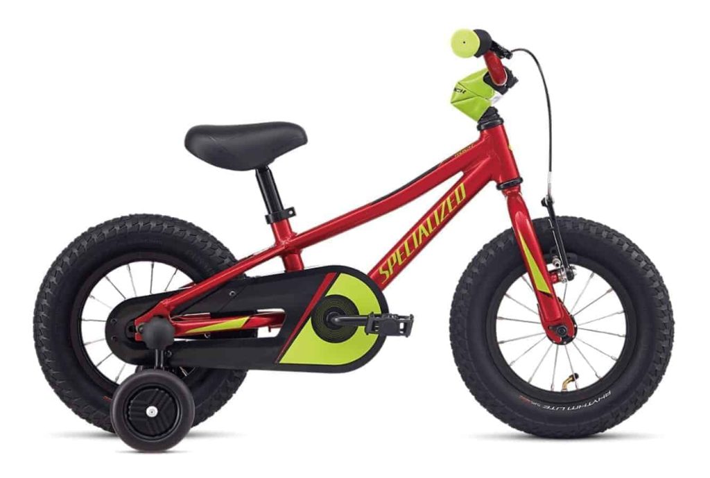 Kleine rode kinderfiets met dikke banden en zijwieltjes van Specialized.