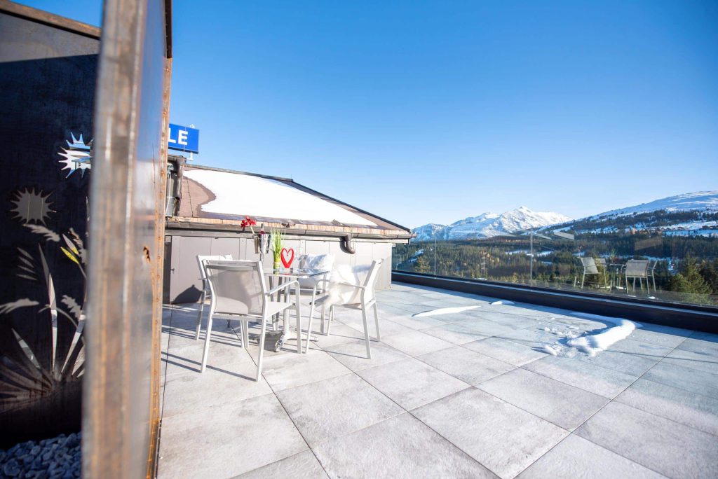 Zonnig terras met uitzicht op besneeuwde bergen in Königsleiten voor de wintervakantie.