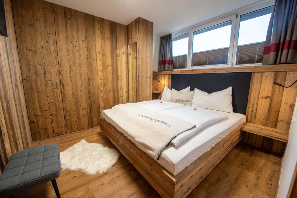 Gezellige slaapkamer met houten lambrisering en modern tweepersoonsbed in Königsleiten.